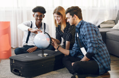 Diverse friends are going for a journey. They are planning using the globe. Bright living room.
